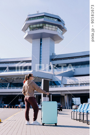 young woman with luggage standing in the airport parking . 90581673