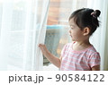 cute little girl is holding the white curtain with copy space 90584122