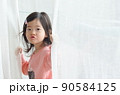 cute little girl is holding the white curtain with copy space 90584125