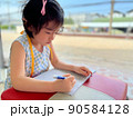 cute little girl writes on her notebook 90584128