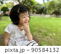 beautiful cute little girl sits and make a pose with smile in the garden with copy space 90584132