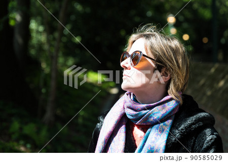 Attractive thirty year old woman posing in the sun, in a Brussels citypark during spring Attractive thirty year old woman posing in the sun, in a Brussels citypark during spring 90585029