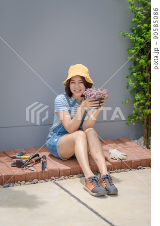 An Asian woman gardener is happy and proud of her planting flowers. An Asian woman gardener is happy and proud of her planting flowers. 90585086