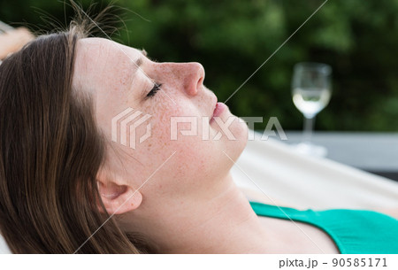 Laeken, Brussels Capital Region - Belgium - Portrait of a young white attractive thirty year old woman lying eyes closed in a hammock 90585171