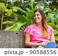 latina woman sitting in a bench in the park 90588556