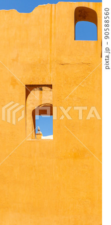 Vertical photo of a yellow wall with windows and blue sky Vertical photo of a yellow wall with windows and blue sky 90588560