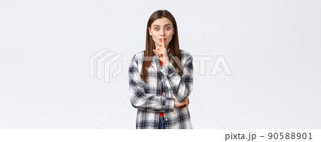 Lifestyle, different emotions, leisure activities concept. Silly cute girl in checked casual shirt asking keep secret, kindly shush with index finger over lips, want person keep voice down, be quiet 90588901