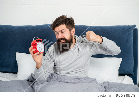 Angry man punching alarm clock being in bed in morning, overslept. Angry man punching alarm clock being in bed in morning, overslept. 90588978