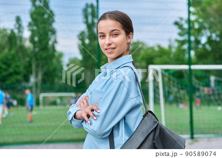 Portrait of teenage female student looking at camera, school stadium background 90589074