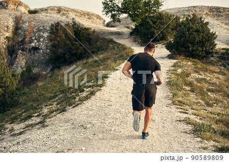 Young muscular male athlete running up the hill 90589809