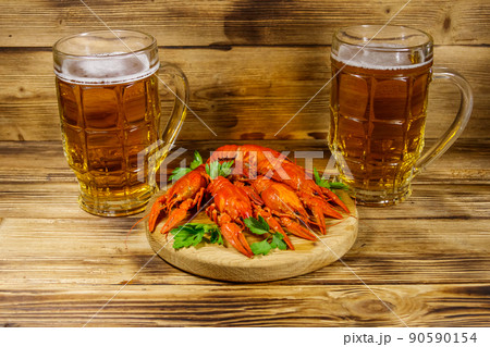 Boiled crayfish and two mugs of beer on a wooden table 90590154