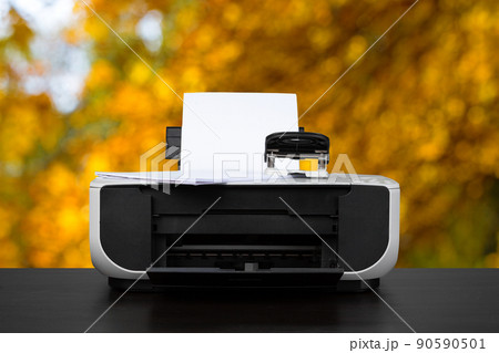 Compact laser printer on black desk against blurred background Compact laser printer on black desk against blurred background 90590501