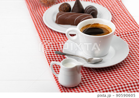 Cup of coffee and saucer with chocolate sweets on wooden table 90590605