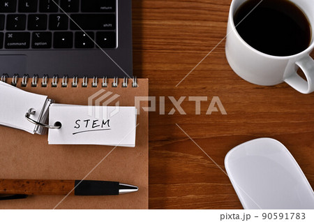 机の上には、クリップボードとノート、そしてSTEMと書かれた単語帳 90591783