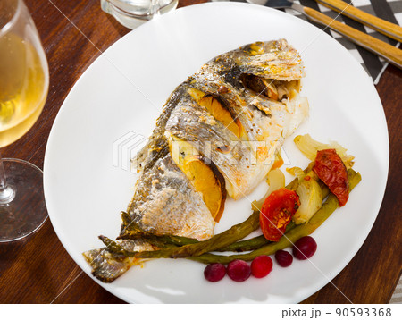 Roasted dorada with baked vegetables and cranberries 90593368