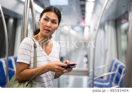 Woman with smartphone in subway train 90593404
