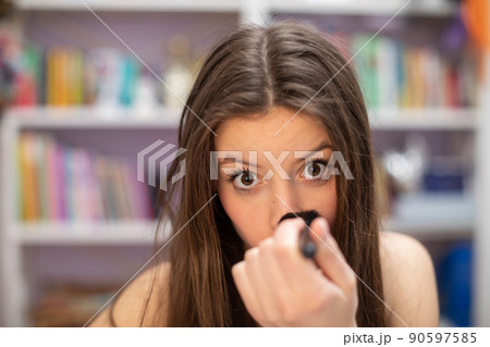 A teenage girl powders her nose as she paints her makeup. Close-up view. A teenage girl powders her nose as she paints her makeup. Close-up view. 90597585