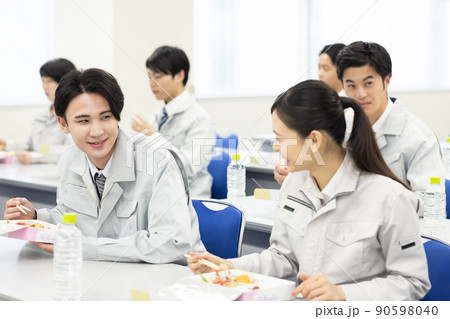 会議室でお弁当を食べる作業着の男女 90598040