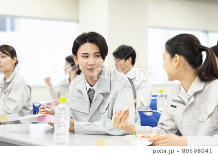 会議室でお弁当を食べる作業着の男女 90598041