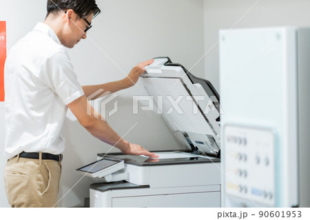 狭い部屋でコピーをとるカジュアル姿のビジネスマン 狭い部屋でコピーをとるカジュアル姿のビジネスマン 90601953