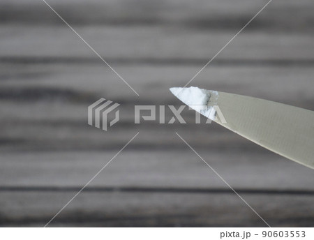 Baking soda on the tip of a metal knife on a wooden background. Baking soda on the tip of a metal knife on a wooden background. 90603553