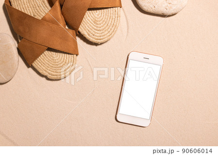 Beach background with mobile phone ,brown sandals and stone on a sandy beach in the sun. Concept: Summer vacation in a warm country.  90606014