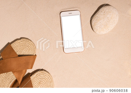 Beach background with mobile phone ,brown sandals and stone on a sandy beach in the sun. Concept: Summer vacation in a warm country.  90606038
