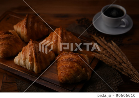 Fresh homemade butter croissant in tray decorated with wheat on wooden table. Levitation, bread bakery products cafe concept 90606610