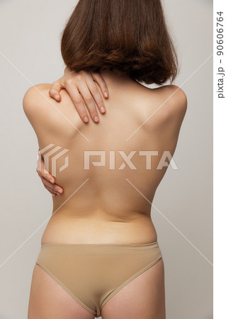 Cropped image of young slim woman posing in underwear isolated over grey studio background. Image of female back Cropped image of young slim woman posing in underwear isolated over grey studio background. Image of female back 90606764