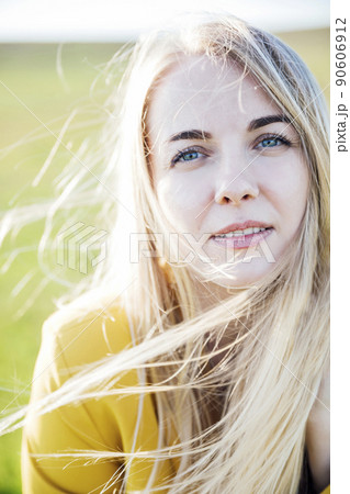 blonde woman walking through a green field at sunset blonde woman walking through a green field at sunset 90606912