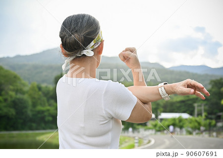 Active aged woman warming up herself before jogging, stretching her arms and body. 90607691