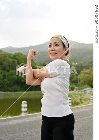 Happy healthy asian aged woman in a sportswear stretching her arms 90607693