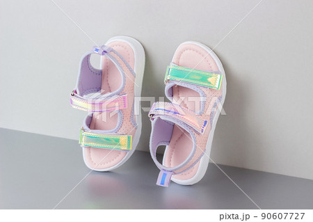 Stylish holographic sandals for kids on grey background. Shiny fashion summer shoes 90607727
