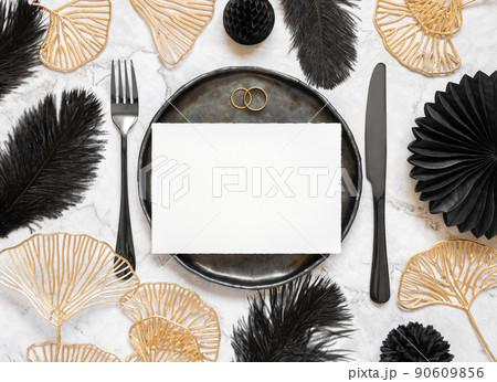 Black and golden wedding table setting with a blank card and rings top view, mockup 90609856