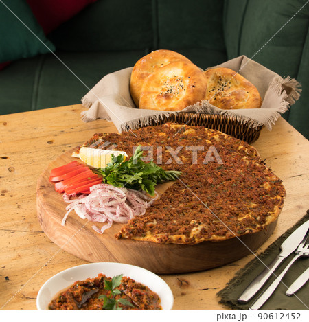 Close up shot of a lahmacun and a salad near basket of breads Close up shot of a lahmacun and a salad near basket of breads 90612452
