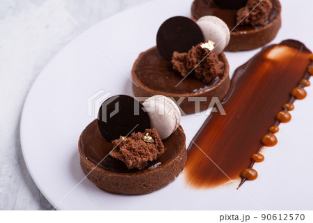 Closeup shot of a delicious chocolate dessert with macaroon served on a white plate Closeup shot of a delicious chocolate dessert with macaroon served on a white plate 90612570