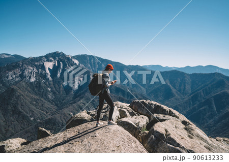 Traveler standing on mountain top and scrolling phone 90613233