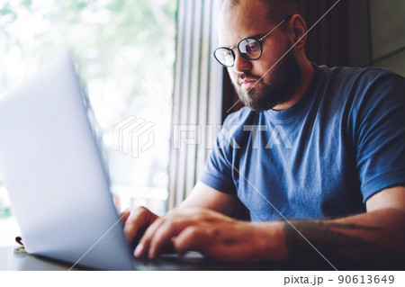 Pensive man browsing laptop working in modern workspace 90613649