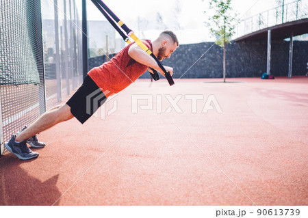Powerful sportsman training with TRX straps 90613739