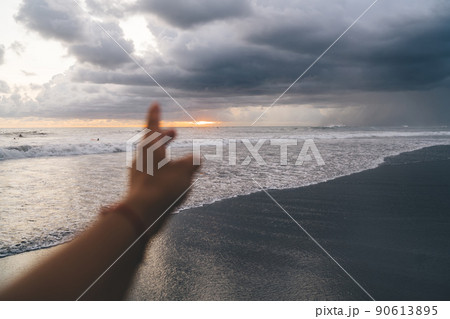 Unrecognizable person admiring sunset from seashore Unrecognizable person admiring sunset from seashore 90613895