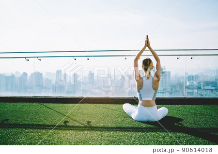 Woman practicing yoga on rooftop in sunny day 90614018
