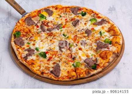 Closeup shot of a freshly baked pizza on a round tray Closeup shot of a freshly baked pizza on a round tray 90614155