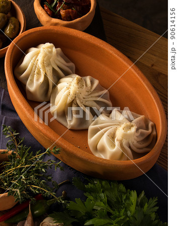 Vertical shot of a luxurious restaurant table with a gourmet khinkali dish Vertical shot of a luxurious restaurant table with a gourmet khinkali dish 90614156