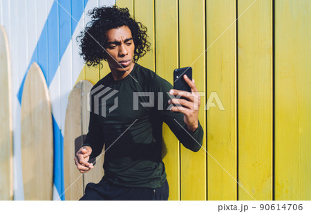 Serious man using mobile phone standing against shabby background Serious man using mobile phone standing against shabby background 90614706