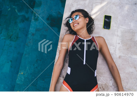 Young woman resting on poolside in summertime 90614970