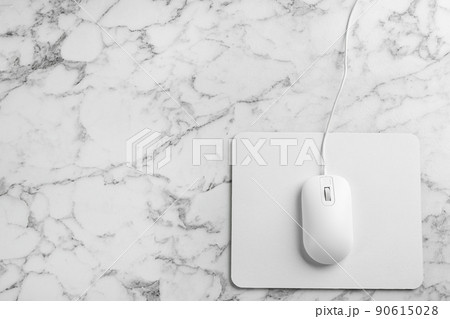 Modern wired optical mouse and pad on white marble table, top view. Space for text 90615028