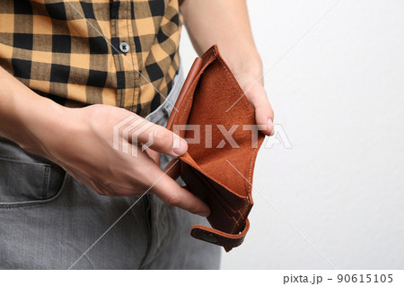Man showing empty wallet on light background, closeup 90615105