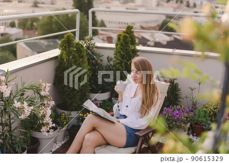 Woman with Coffee Reading Book on Rooftop Garden 90615329