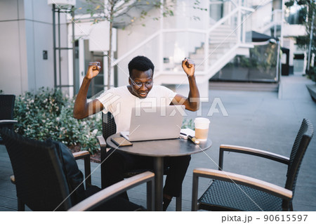 Positive dark skinned male feeling happy about successful project outdoors Positive dark skinned male feeling happy about successful project outdoors 90615597