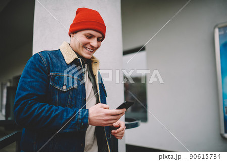 Happy man messaging on smartphone on street 90615734